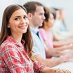 Students at computer class. Focus is on happy young woman looking at the camera.