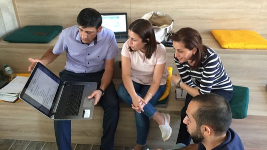 Group of people sitting together and looking at a presentation on a notebook