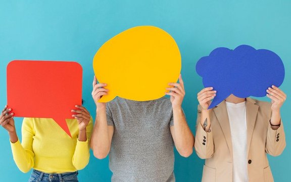 people holding up paper-cuts of speech bubbles