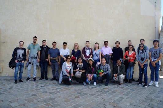 OeAD scholarship holders stand on the wall of a building in Graz. 