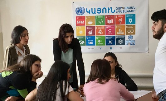 Group of people discussing something in front of a SDG poster