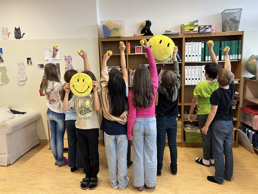 Schülerinnen und Schüler halten Smiles in die höhe