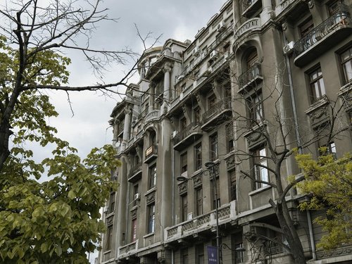 Alte Häuserfassade vor Bäumen in Bukarest
