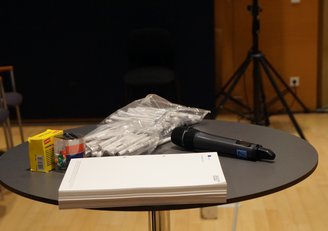 Kugelschreiber, Blöcke und Mikrofon liegen auf einem Tisch