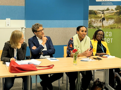 Four participants sitting at a table, one woman is talking