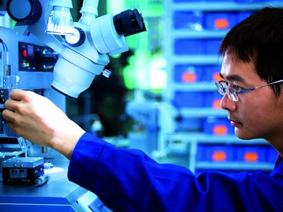 Young student adjusts a microscope.