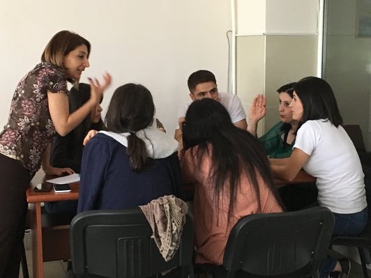 Group of people sitting and standing around a table are discussing something