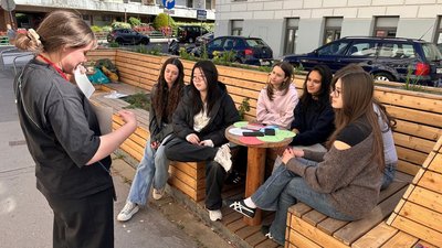 Mehrere Personen sitzen und betrachten eine stehende Person, die eine Aufgabe erklärt
