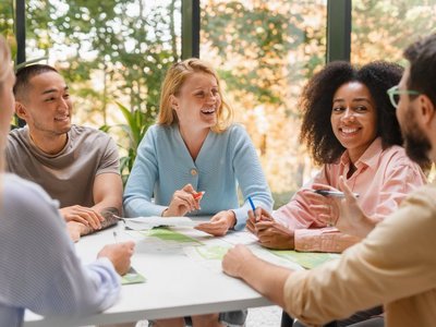 Mehrere Personen sitzen um einen Tisch und unterhalten sich