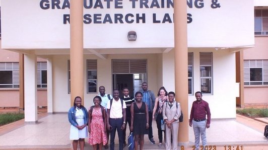 Group picture of students and staff in front of a university building