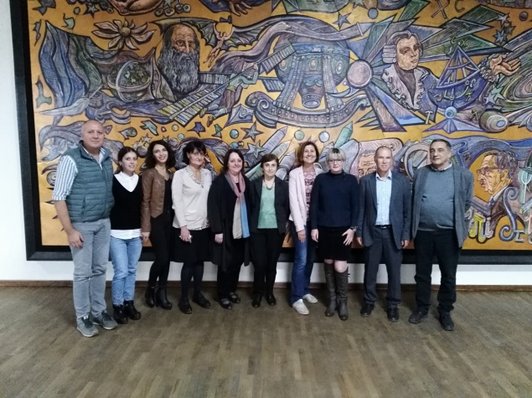 Group of people posing for a group picture in front of an artwork