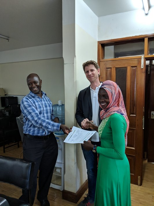 Three people posing for a picture and holding a slip of paper 