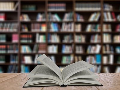 Aufgeschlagenes Buch auf Tisch in einer Bibliothek