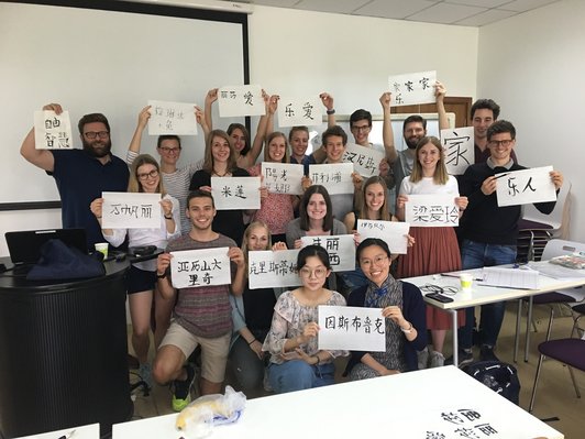 Group of students with Chinese characters on paper in their hands in a classroom