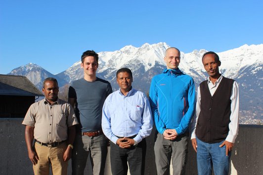 Group of people posing for a picture in front of snow coverd mountains