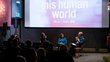 picture shows people in the cinema sitting, listening and watching the two panellists who are sitting in the front of the room