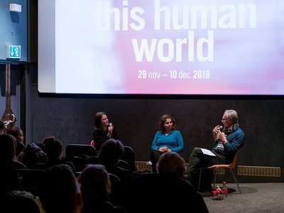 picture shows people in the cinema sitting, listening and watching the two panellists who are sitting in the front of the room