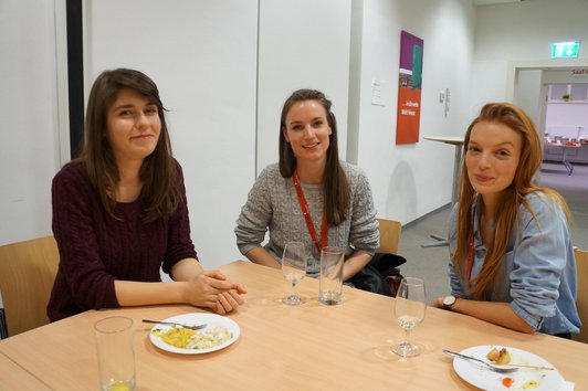 Drei Stipendiatinnen am Tisch mit Essen und Trinken