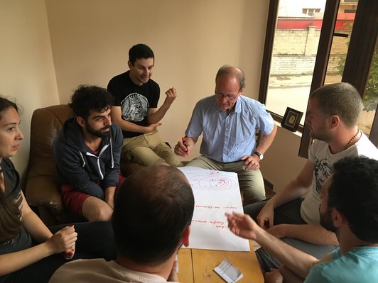 Group of people sitting around a table and working on a poster