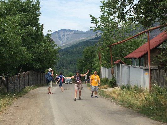 Group of people walking on a bituminized street in green surroundings