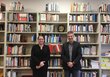 Two people stand in front of a large bookshelf