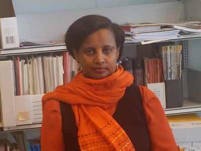 Elshaday Kifle Woldeyesus standing in front of a book shelf