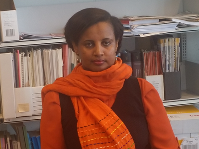 Elshaday Kifle Woldeyesus standing in front of a book shelf