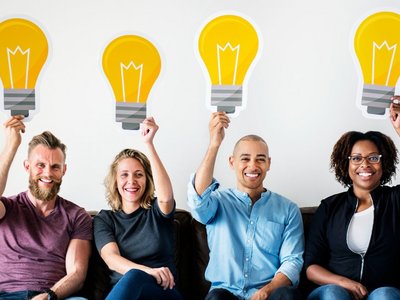 Vier Personen, die jeweils eine Illustration einer großen Glühbirne über sich halten