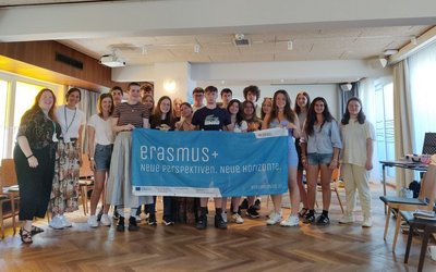 Gruppe junger Menschen hält "Erasmus+" Banner in die Kamera 