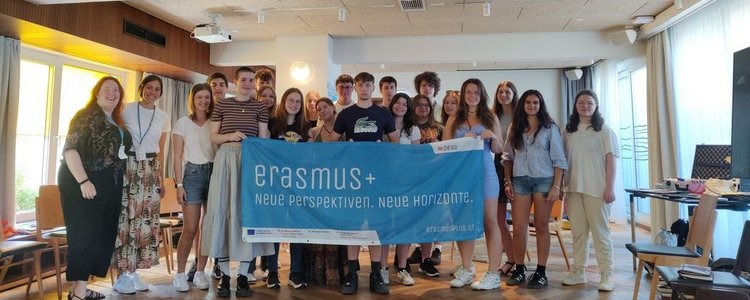 Gruppe junger Menschen hält "Erasmus+" Banner in die Kamera 