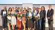 Group photo of the award winners including women and men, everyone holds certificates and bouquets.