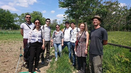 GRoup of people posing for a picture on the field in green surroundings