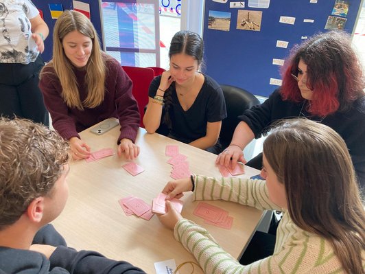 Fünf Personen sitzen um einen Tisch herum