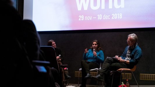 young female panellist talkint to the audience in the cinema and people in the front rows listening to her