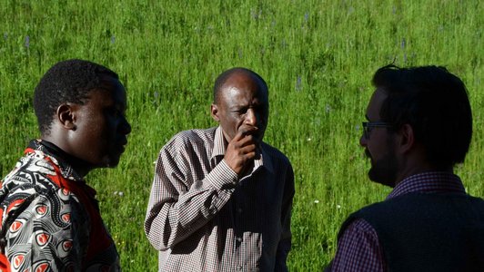 Three Peolpe standing in green surroundings looking to each other