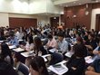 Großer Saal mit vielen Tischen, die in Reihen stehen und vielen thailändischen Studenten.