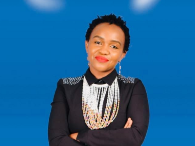 Sonnia Musyoka sitting on a chair in front of a blue background