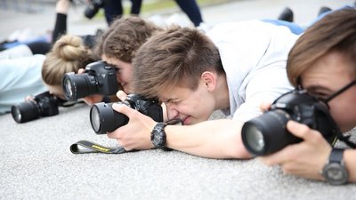 Drei junge Männer halten jeweils eine Kamera nah am Boden 