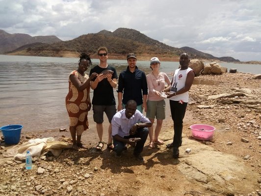 Group of people posing for a group picture in front of a lake