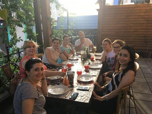 Group of people is sitting around a table and look into the camera for a picture