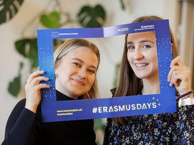 Zwei Frauen schauen durch einen Rahmen aus Papier