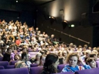 Ein voller Kino Saal mit violetten Sesseln.