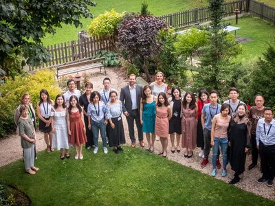 OeAD-Geschäftsführer Stefan Zotti und Regina Aichner mit chinesischen Stipendiat/innen beim European Forum Alpbach 2018. Sie stehen in einem von grünen Wiesen und Bäumen umsäumten Weg.