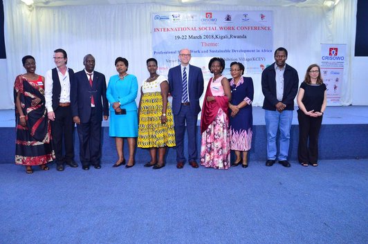 Grop of people posing for a group photo in front of a conference poster