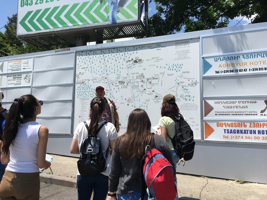 Group of people standing in front of a big information board 