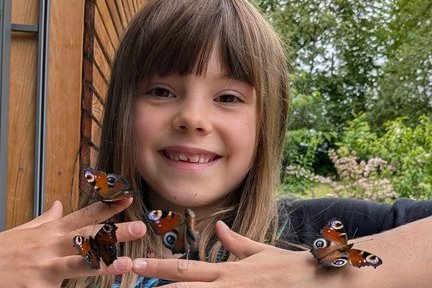 Mädchen mit vier Schmetterlingen auf seinen Händen
