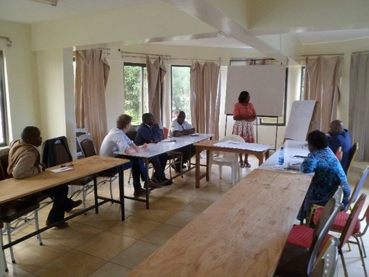 People sitting at tables arranged in U-form, a woman standing in front