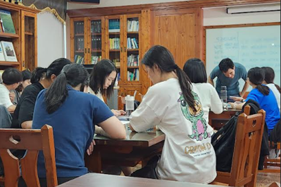 Eine Gruppe junger Frauen (von hinten und von der Seite) gemeinsam an einem Tisch in einem Klassenraum