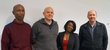 Four people standing in front of a white wall 