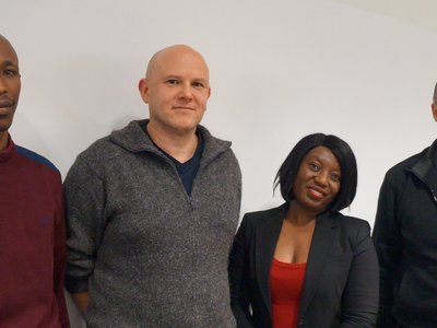 Four people standing in front of a white wall 